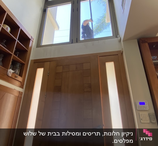 אדם מנקה חלון גבוה עם מגב